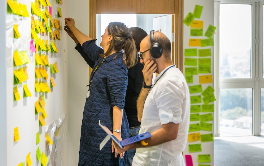 DDaT team reviewing work on a wall in the office