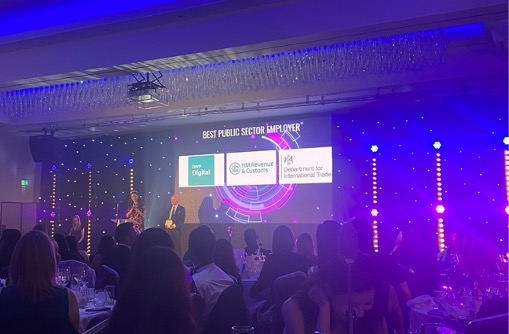 Screen at the Women in Tech Awards ceremony showing the nominees for Best Public Sector employer: DWP Digital, HMCR and Department for International Trade