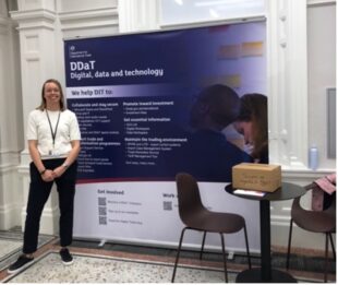 Sanna Huovinen, Product Manager, standing with our DDaT Week banner in the OAB café.