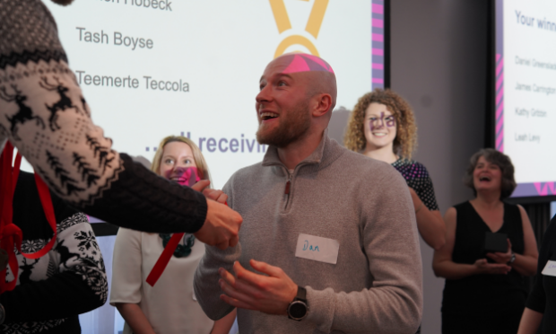 A male colleague being presented with an award.