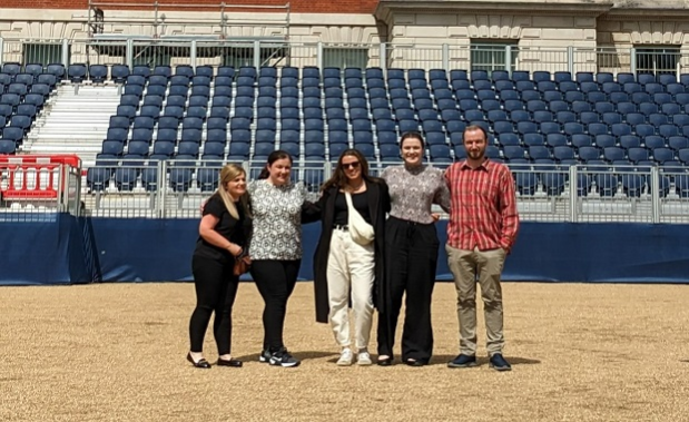 5 people stood outside in front of a stand of blue seating