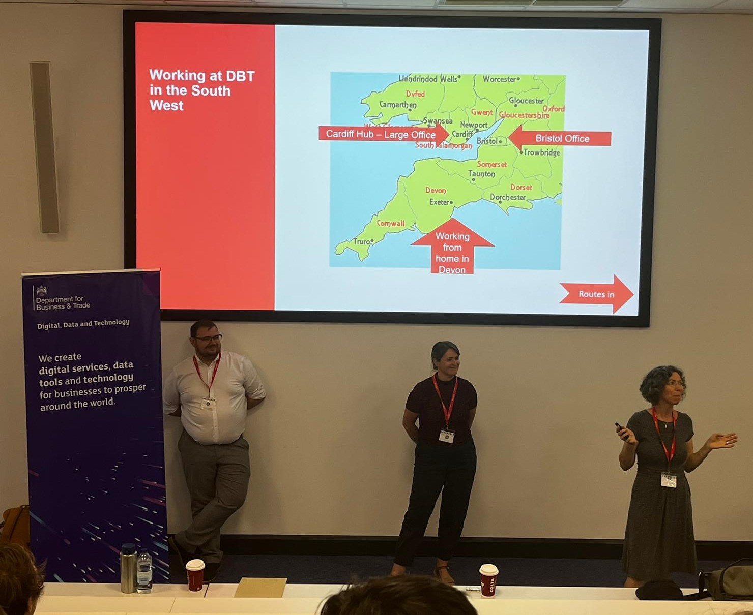 A man and 2 women stood in front of a big screen with a map of South West England