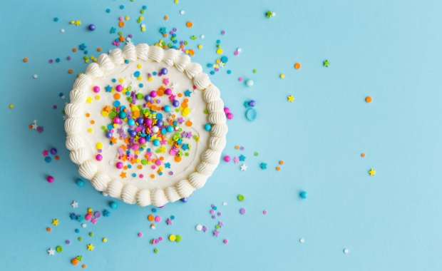 A cake covered in confetti against a blue background