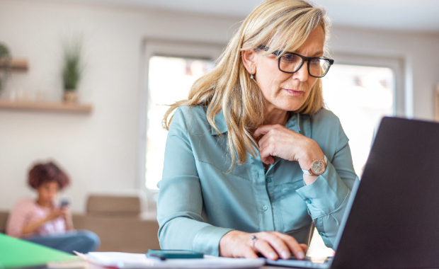 A lady wearing glasses sat down looking at a laptop