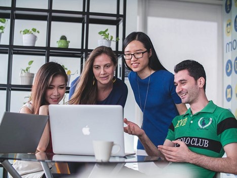 Image of four people looking at a laptop 