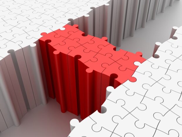Red jigsaw pieces building a bridge between white pieces