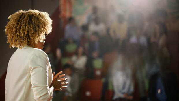 A smartly dressed woman addressing a conference audience