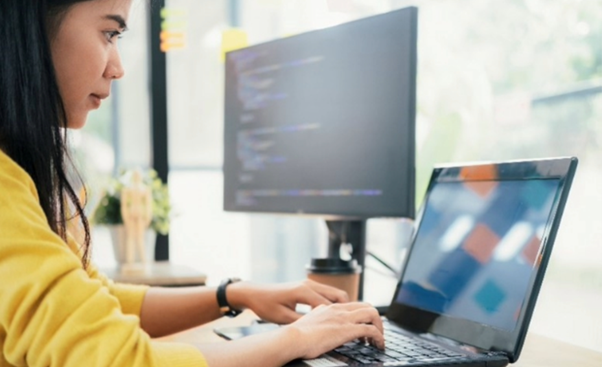 Woman in a yellow top working on a laptop