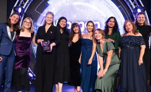 A group of 10 happy women in gorgeous evening dress with a Women in Leadershop award